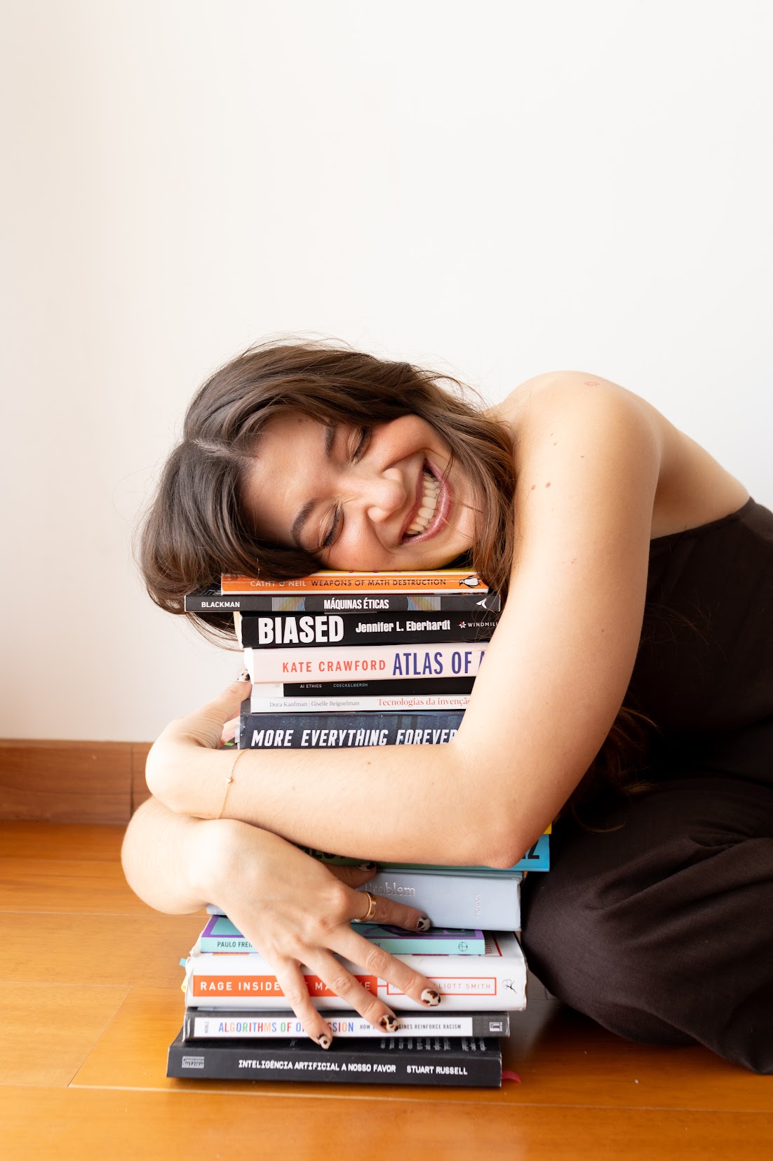 Catharina Doria hugging a tall stack of responsible AI books